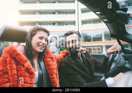Happy couple having fun inside convertible car in holidays vacation - Fashion traveling together - Trendy, trip and relationship concept - Vsco filter Stock Photo