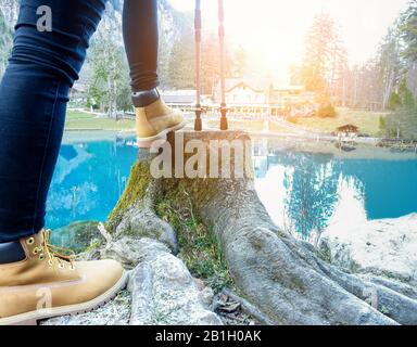 Young woman doing trekking with blue lake and chalet in background - Hiker enjoying summer season mountain sport - Healthy lifestyle and nature concep Stock Photo
