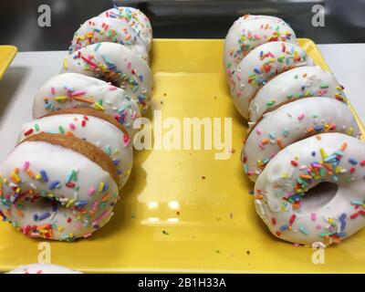 Close up of delicious colorful donuts with confetti. assorted donuts with chocolate frosted, pink glazed and sprinkles donuts. Selective focus. Stock Photo