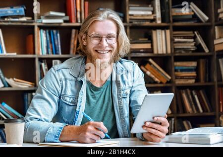 Student hold modern tablet make notes in notebook empty smile at camera Stock Photo