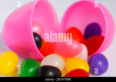 Colorful jelly beans spill out of plastic Easter eggs Stock Photo