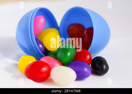 Colorful jelly beans spill out of plastic Easter eggs Stock Photo