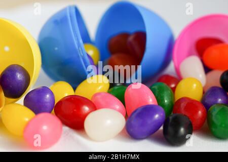 Colorful jelly beans spill out of plastic Easter eggs Stock Photo