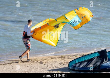 Ninh Chu Beach, Ninh Thuan Province, Vietnam - January 9, 2020: A man with a large yellow kite on a beach in Ninh Chu. Kite surfing is a sport that is Stock Photo