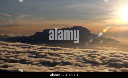 View of the peak of Mount Kinabalu, Sabah, Malaysia, surrounded by sea of clouds, in the morning sun. Stock Photo