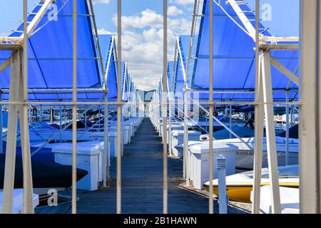 Boats line up symmetrically in their private boats slips behind a gated entry at the resort marina at Coeur d'Alene, Idaho, USA. Stock Photo