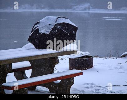 Snow covered umbrella rests on picnic table during snow storm Stock Photo