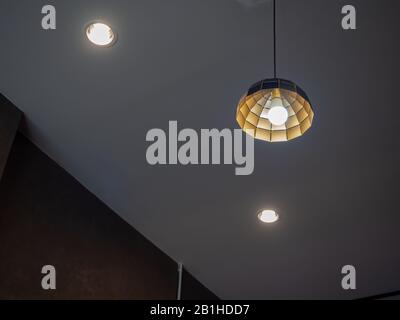 Modern ceiling light hanging from ceiling with downlight in dark room. Stock Photo