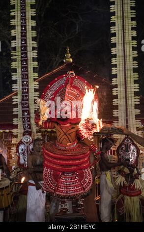 Theyyam performer, as a living god, dances a popular ritual form of worship in North Kerala, near Kannur, India. Stock Photo