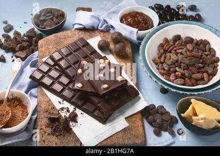Dark bitter chocolate bars, cacao butter, cacao powder and cocoa beans on blue background. Chocolate background. Stock Photo