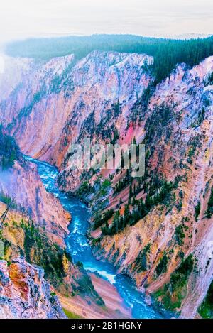 Looking down into canyon with blue river running through canyon under a misty sky. Stock Photo