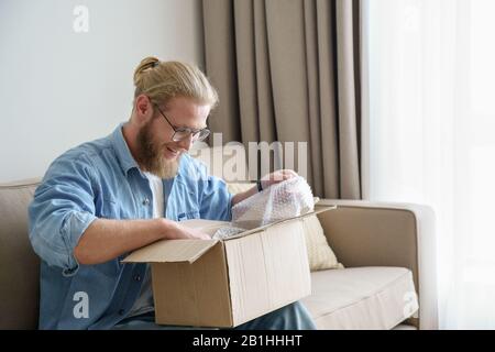 Happy male customer open cardboard box receive postal mail delivery package Stock Photo