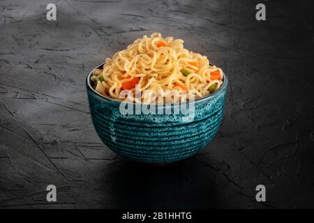 Instant noodles with carrot and scallions, a bowl of soba with vegetables on a black background Stock Photo