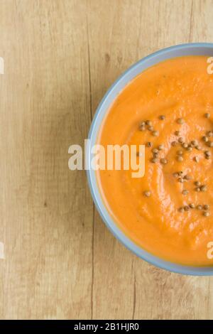 Top view of pumpkin soup in blue bowl on wooden background. Vertical photo with copy space Stock Photo