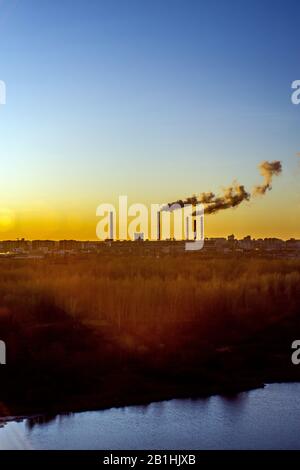 Smoking industrial chimneys at dawn. Concept for environmental protection Stock Photo