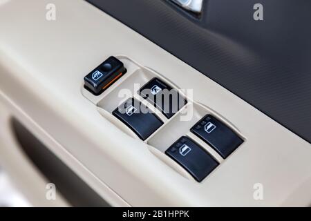 The control buttons for opening and closing windows of doors and electric controls on the door in gray with upholstery in a luxury modern car. Stock Photo