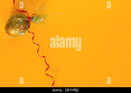 Easter egg and festive ribbon on the yellow background. View from above. Top view. Flat lay image of easter festive holiday background. Concept of Stock Photo