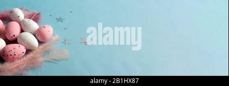 Banner easter pink eggs with feathers. Blue backdrop. Stock Photo