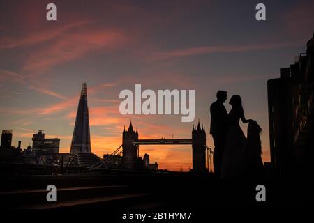 Bride and groom wedding photo of a couple silhouette at sunset with Tower Bridge and the Shard behind them. Beautiful sunset colours over London Stock Photo
