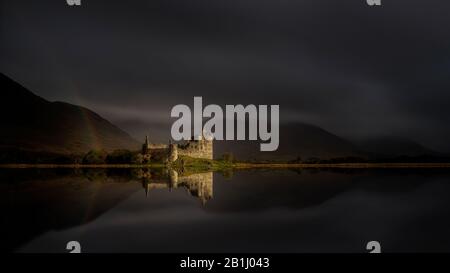 Dramatic sunlit Kilchurn Castle with rainbow, reflected on loch awe near Dalmally and Oban Scotland. 15th Century ruined castle Stock Photo