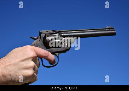 Man holding a .44 or .45 caliber revolver outdoors with blue sky. Stock Photo