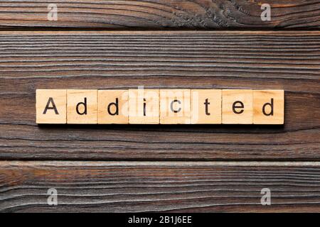 Addicted word written on wood block. Addicted text on wooden table for your desing, Top view concept. Stock Photo