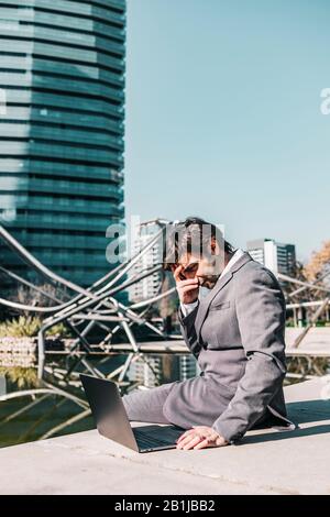 Frustrated businessman looking his laptop outdoors Stock Photo