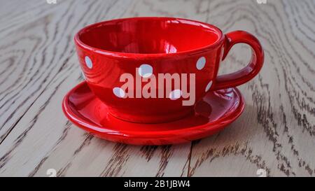 Red cup with white peas on a saucer standing on a wooden background Stock Photo