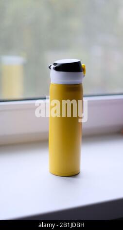 yellow thermos with black standing on the window Stock Photo