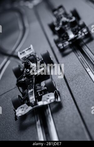 Model formula one style slot cars racing on a Scalextric track in blue tinted monochrome Stock Photo