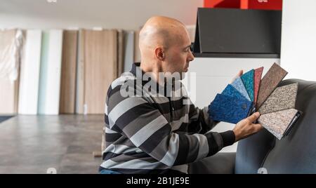 The man selects a new cover for the sofa from the color card sampler Stock Photo