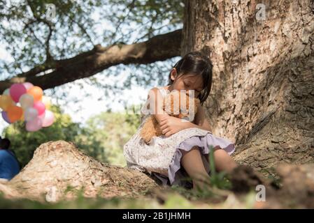 Sad girl feeling alone in the park. Lonely concepts. Beautiful toddler girl  and fluffy stay alone under the big tree Stock Photo - Alamy