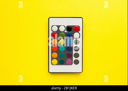 Small unusual control or remote panel with multi-colored buttons on a bright clear yellow background. Flat-lay, top view, mockup Stock Photo