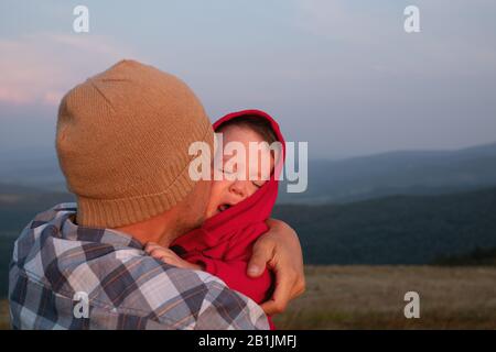 The son sits on his fathers shoulders in the spring mountains. Family camping. Travel with child concept Stock Photo