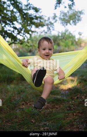 Small kid on yellow hammock in spring forest. Travel with child concept Stock Photo