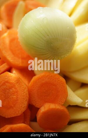 Raw onion and round slices of carrots and potatoes close-up. Set of vegetables for soup. Healthy vegan food. Stock Photo