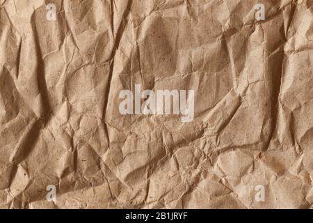 Close up of a piece of brown crumpled wrapping paper with rough folds and bends. Abstract modern trendy paper texture background Stock Photo