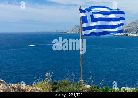 Beautiful Mediterranean landscape with a Greek flag flying in the wind on a sunny day (Rhodes, Greece) Stock Photo