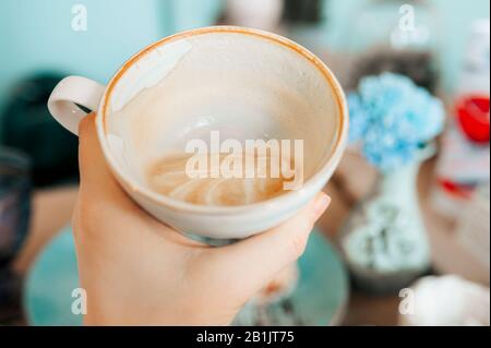 half-empty white elegant porcelain Cup with cappuccino coffee, the remnants of foam on the walls of the mug. Eating in a beautiful cafe in mint colors Stock Photo