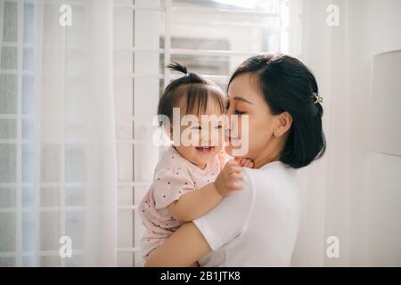 Portrait of happy vietnamese mother hugging with her cute little daughter at home Stock Photo