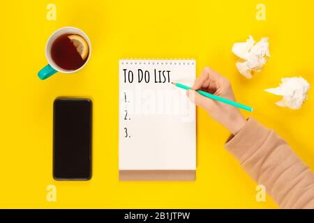 To do list. Mint Tea cup and notebook with to do list on bright yellow desk from above, planning and design concept. Top view, flat lay, copy space. M Stock Photo
