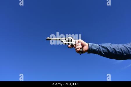 Man holding a .44 or .45 caliber revolver outdoors with blue sky. Stock Photo