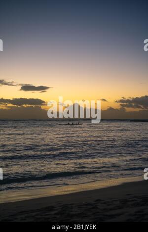 Rowers Silhouetted in Outrigger Canoe in Hawaii at Sunset Stock Photo