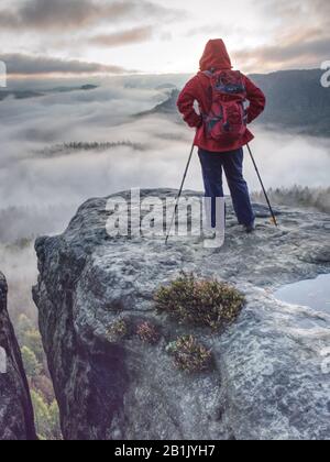 Hiker found attractive place on trail in sandstone rocky towers. Autumn misty morning in pure nature. Tourist use outdoor equipment Stock Photo