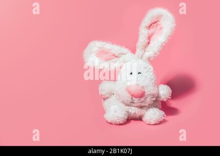 Adorable stuffed bunny on pink background with copy space. Minimal Easter concept. Stock Photo