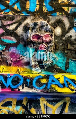 Scary maked man emerging from graffiti covered brick wall, Hosier Street, Melbourne Lanes, Melbourne, Victoria, Australia Stock Photo