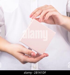 Delicate pink box with a gift in female hands on a white background. Holiday, March 8, Valentine's Day concept. Mock up Stock Photo