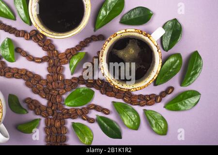 A tree-shaped layout made from coffee beans with cups of coffee grown on it. Top view layout. Stock Photo