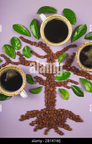 A tree-shaped layout made from coffee beans with cups of coffee grown on it. Top view layout. Stock Photo