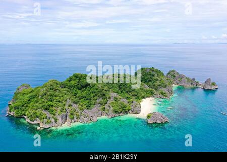 Tropical landscape: Matukad Island with beautiful beach and tourists by turquoise water view from above. Caramoan Islands, Philippines. Summer and travel vacation concept. Boats and tourists on the beach. Stock Photo